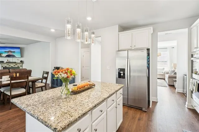 a kitchen with stainless steel appliances granite countertop a stove top oven a sink dishwasher and white cabinets with wooden floor