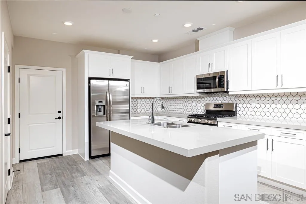 1174 Delpy View Point, Unit 102 Vista, CA 92084 - Photo 6 of 17 a kitchen with a sink a stove a refrigerator a center island and a stove