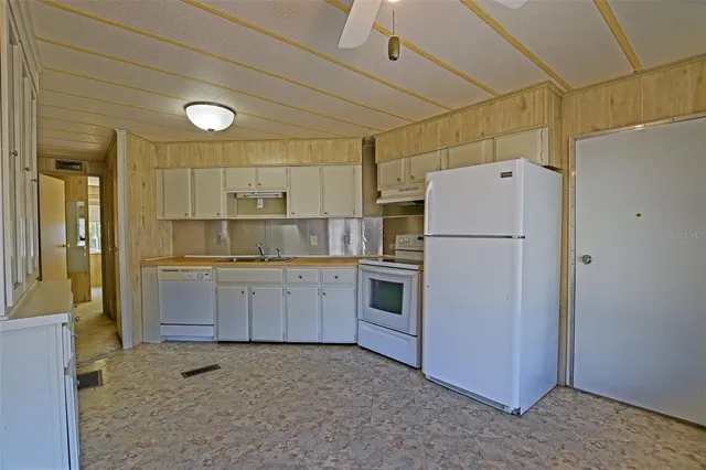 a kitchen with a refrigerator a stove top oven and white cabinets