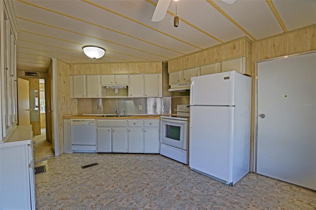 7452 Southeast 135th Street Summerfield, FL 34491 - Photo 24 of 43 a kitchen with a refrigerator a stove top oven and white cabinets