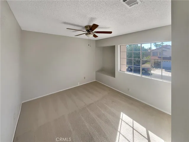 an empty room with windows and fan