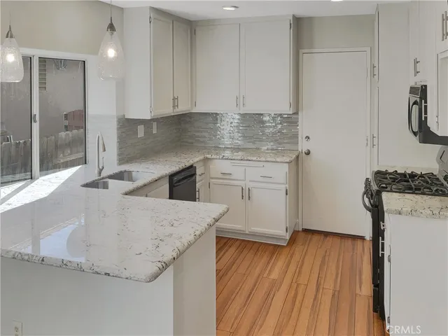 a kitchen with granite countertop a sink a stove and refrigerator