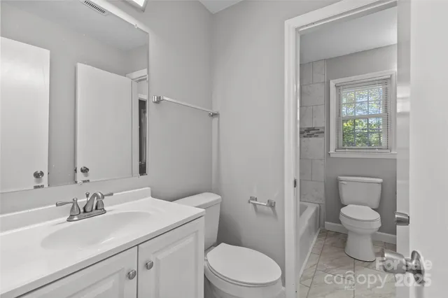 a bathroom with a granite countertop toilet a sink and a mirror