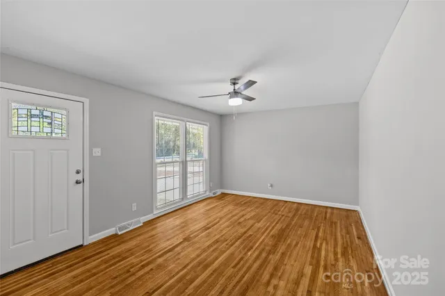 a view of an empty room with wooden floor and a window