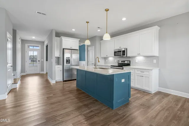 a large kitchen with stainless steel appliances kitchen island a stove a refrigerator a sink dishwasher a oven and a dining table with wooden floor