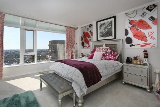 a spacious bedroom with a bed painting on the wall and a large window