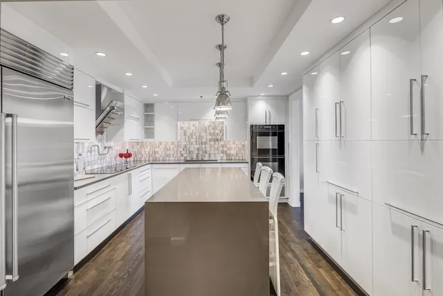 a large kitchen with kitchen island white cabinets and stainless steel appliances