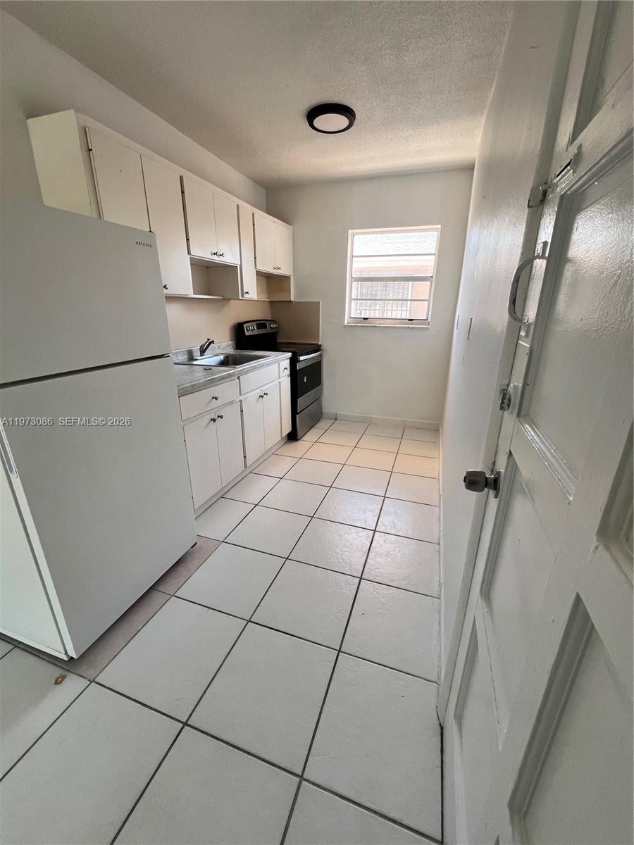 608 Southwest 15th Avenue, Unit 2 Miami, FL 33135 - Photo 7 of 22 a kitchen with granite countertop a refrigerator a sink a stove a microwave and cabinets