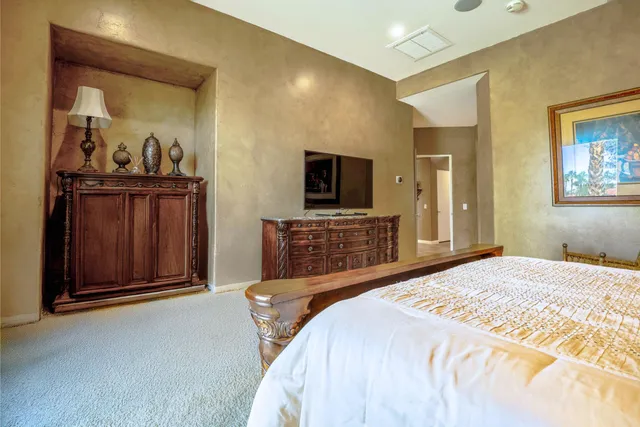 a spacious bedroom with a bed and a flat screen tv