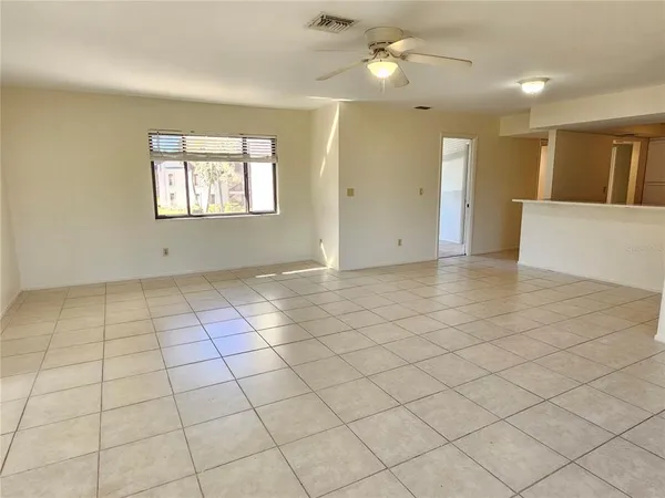 an empty room with windows and ceiling fan