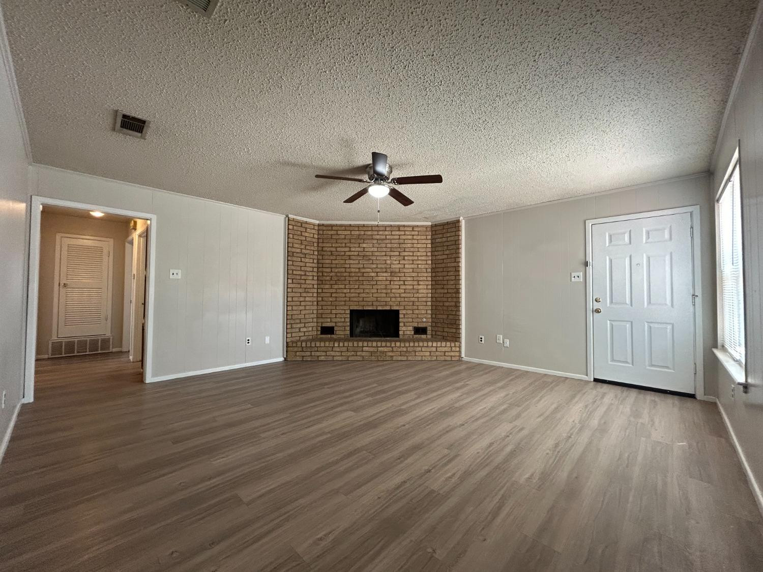 4812 66th Street, Unit B Lubbock, TX 79414 - Photo 2 of 9 a view of an empty room with wooden floor and a fireplace