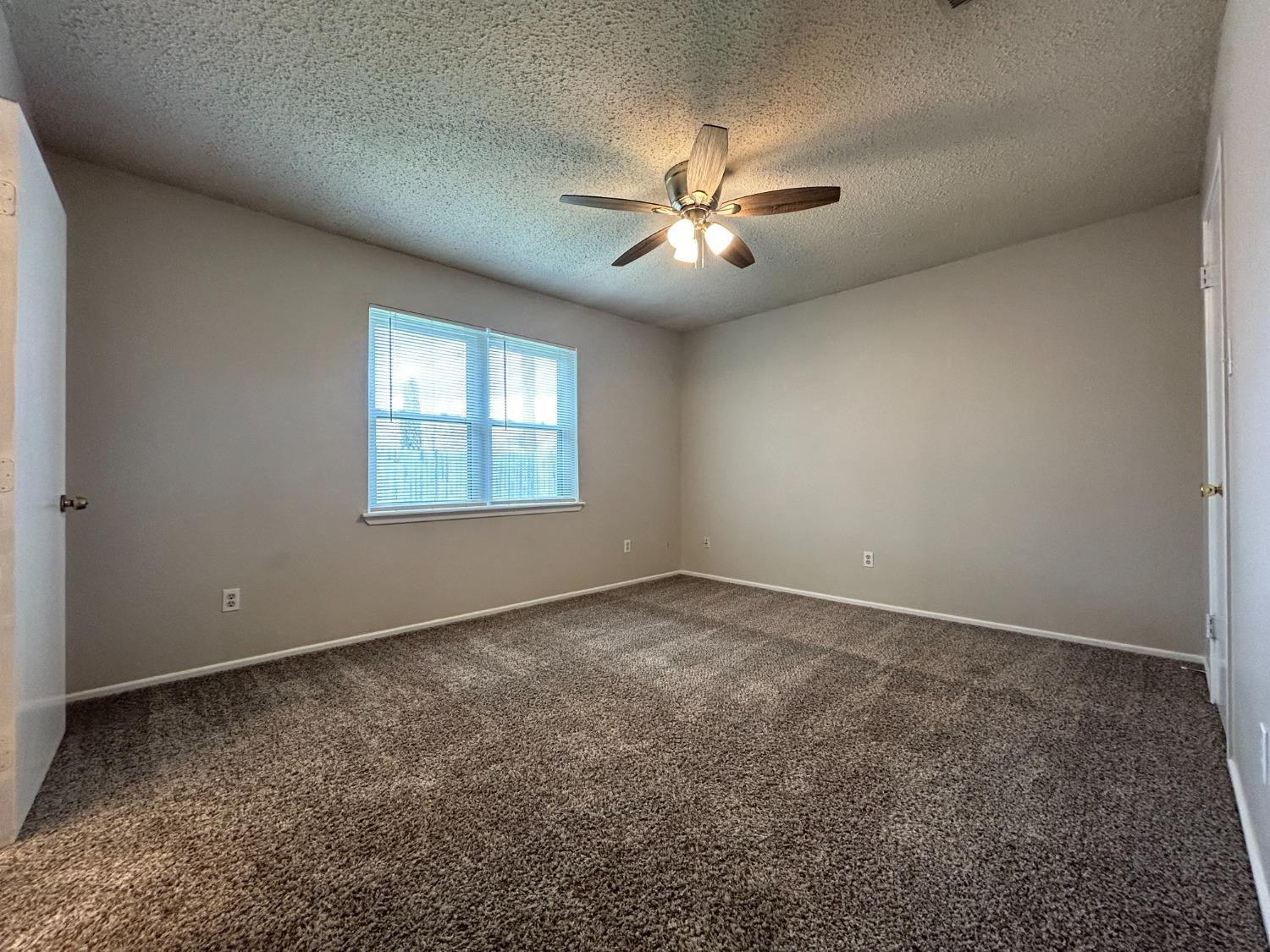 4812 66th Street, Unit B Lubbock, TX 79414 - Photo 5 of 9 an empty room with windows and fan