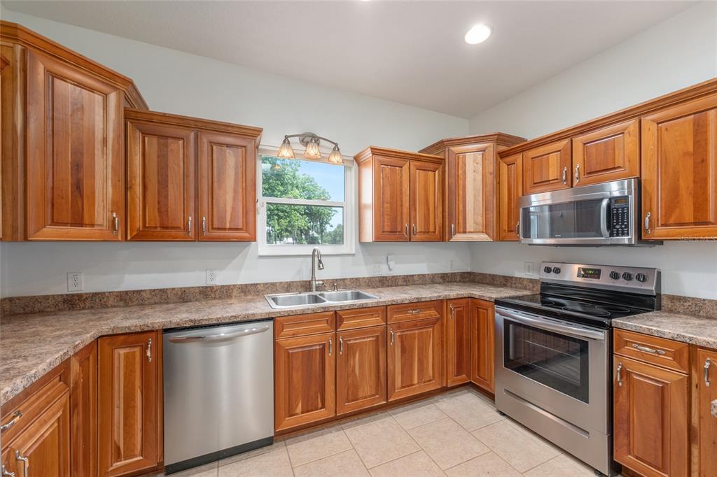 4735 Southeast 112th Street Road Belleview, FL 34420 - Photo 26 of 73 a kitchen with stainless steel appliances granite countertop a sink stove and microwave