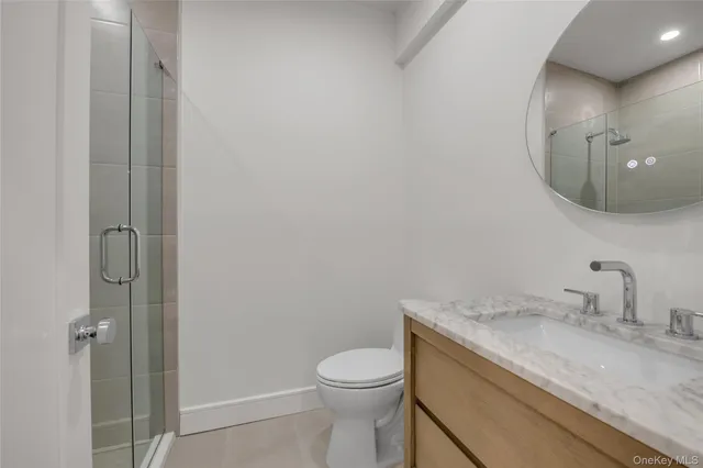 a bathroom with a granite countertop sink mirror vanity and toilet