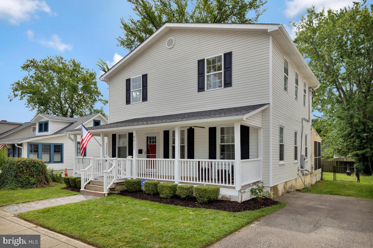 a view of a white house with a yard and large trees