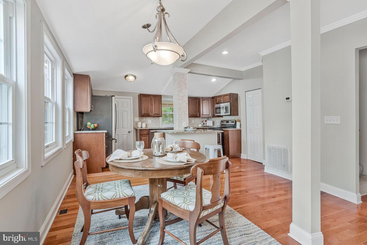 4037 7th Street North Beach, MD 20714 - Photo 25 of 54 a dining room with stainless steel appliances kitchen island granite countertop a dining table chairs and a refrigerator