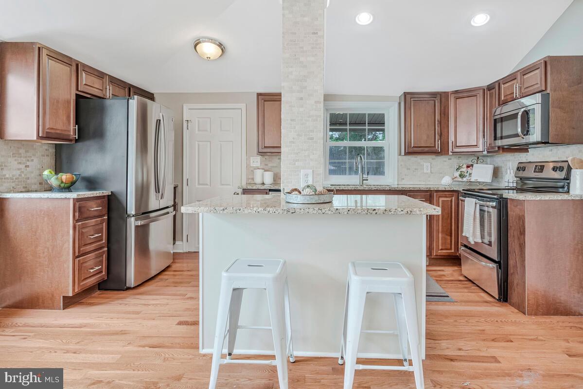 4037 7th Street North Beach, MD 20714 - Photo 28 of 54 a kitchen with stainless steel appliances granite countertop a refrigerator a stove top oven a sink dishwasher and wooden cabinets with wooden floor
