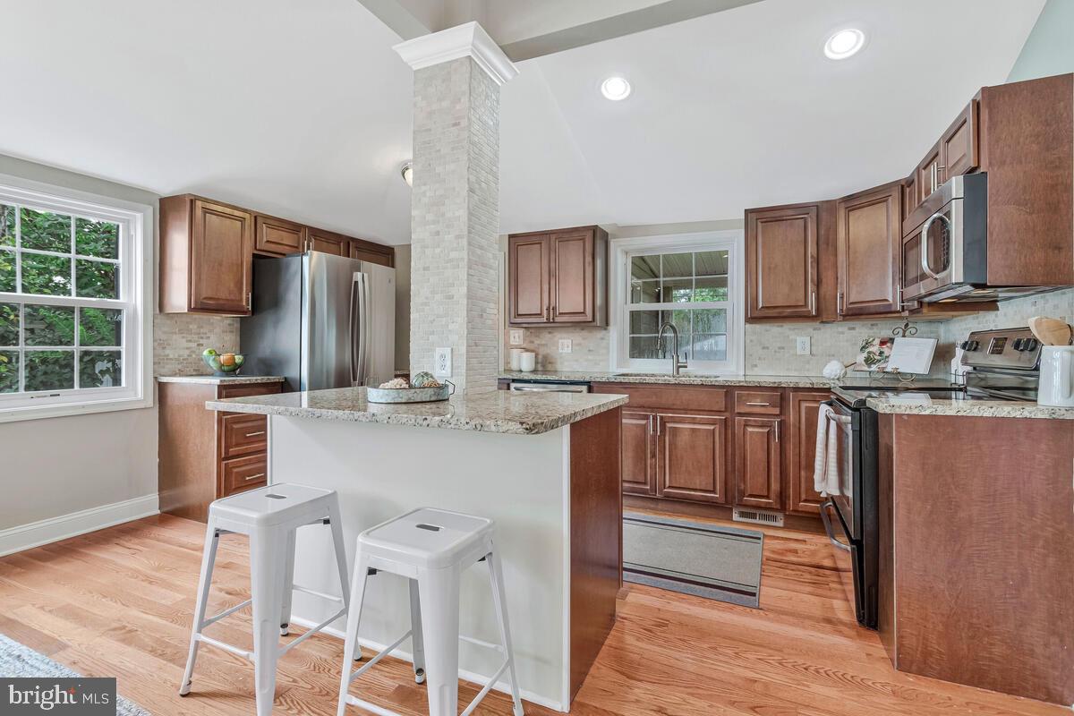 4037 7th Street North Beach, MD 20714 - Photo 29 of 54 a kitchen with stainless steel appliances wooden cabinets a stove a sink and a refrigerator