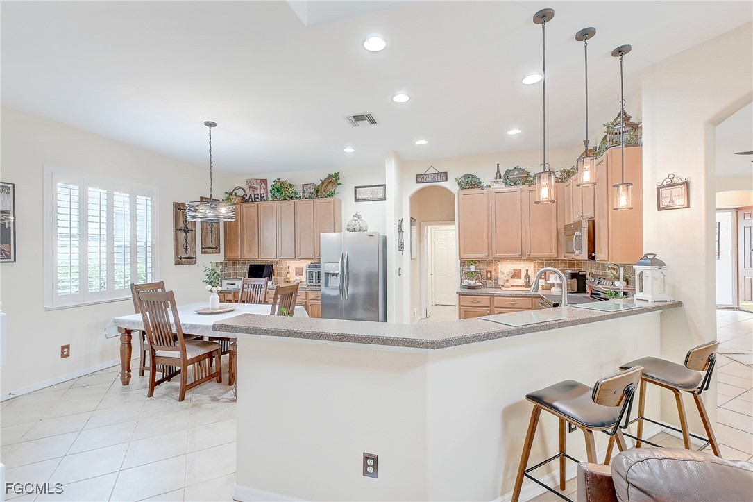 12890 Timber Ridge Drive Fort Myers, FL 33913 - Photo 6 of 39 a kitchen with stainless steel appliances kitchen island granite countertop a table and chairs