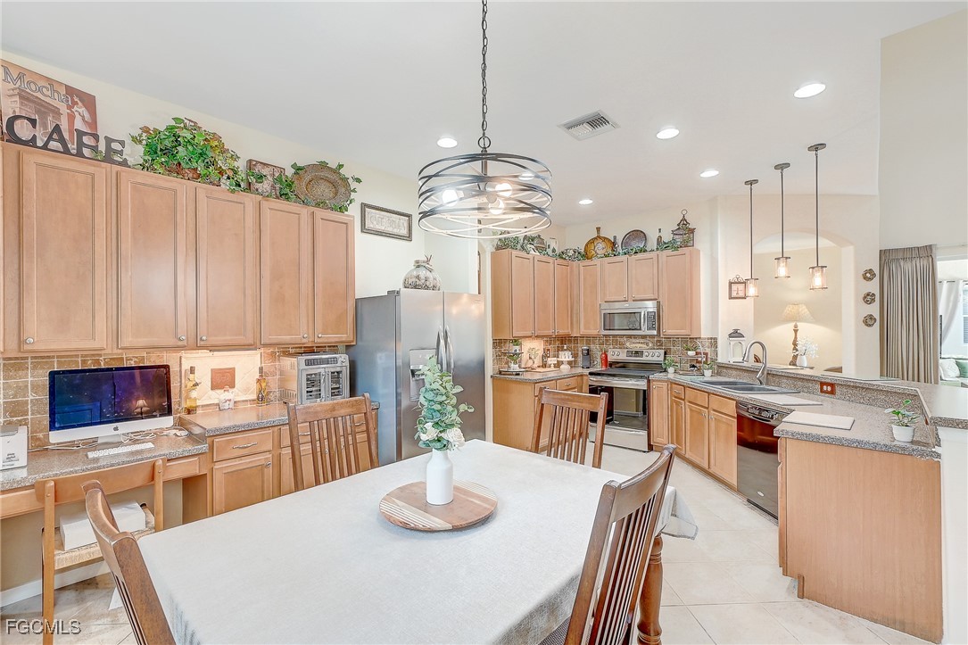 12890 Timber Ridge Drive Fort Myers, FL 33913 - Photo 7 of 39 a kitchen with stainless steel appliances granite countertop a stove a sink dishwasher a dining table and chairs with wooden floor