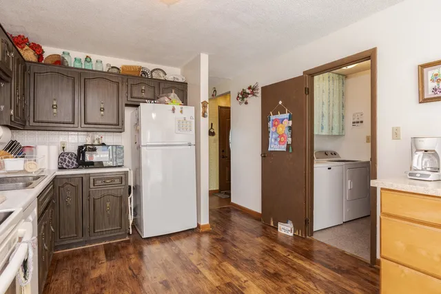 a kitchen with stainless steel appliances granite countertop a stove a refrigerator and a sink with wooden floors