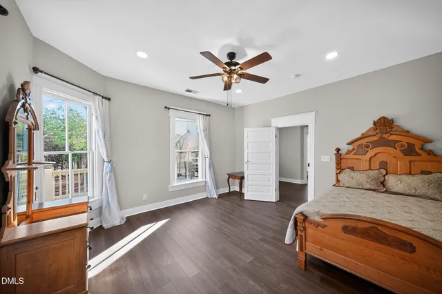 a bedroom with a bed a dresser and potted plants with wooden floor