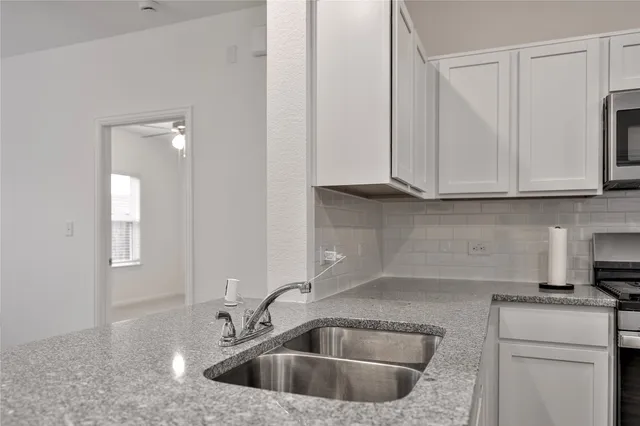 a kitchen with stainless steel appliances granite countertop white cabinets a sink and dishwasher