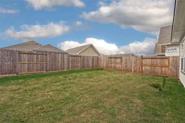 a view of a backyard with a garden and wooden fence