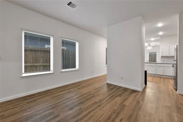 a view of an empty room with wooden floor and a window