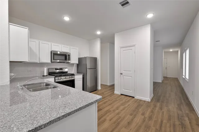 a kitchen with stainless steel appliances granite countertop a refrigerator a stove top oven a sink dishwasher and microwave with wooden floor