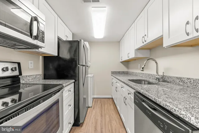 a kitchen with granite countertop white cabinets and a sink