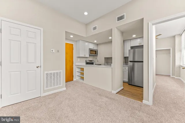 a view of a kitchen with refrigerator and white cabinets