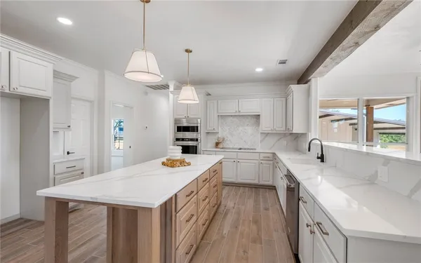 a kitchen with a sink a center island a stove cabinets and a chandelier
