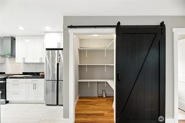 a kitchen with a refrigerator and white cabinets