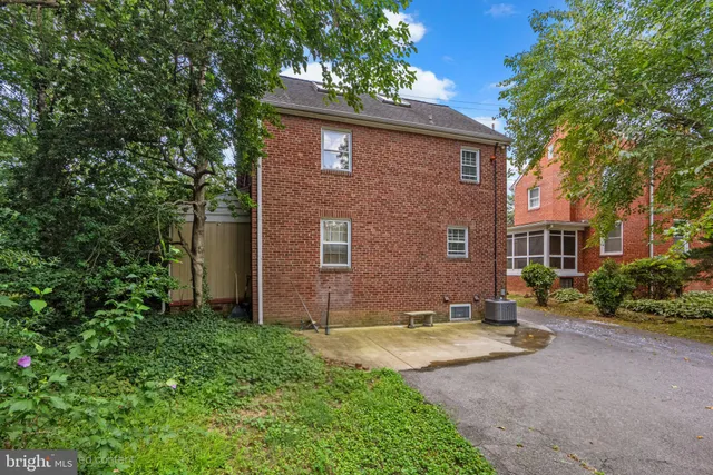 a view of a brick house with a yard and large tree