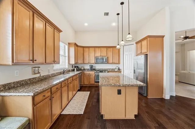 a kitchen with stainless steel appliances granite countertop a sink a refrigerator and wooden cabinets
