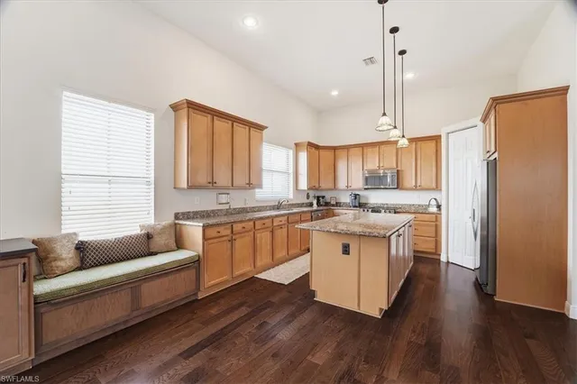 a kitchen with stainless steel appliances granite countertop wooden floors and white cabinets