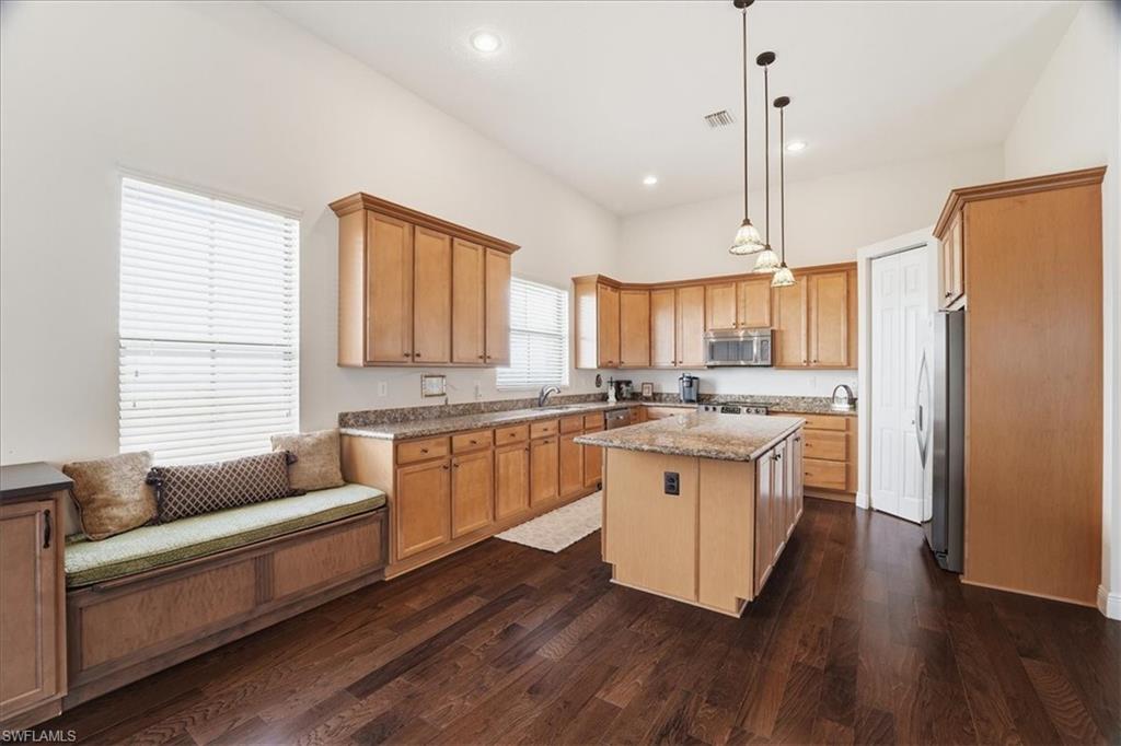 5149 Roma Street Ave Maria, FL 34142 - Photo 17 of 50 a kitchen with stainless steel appliances granite countertop wooden floors and white cabinets