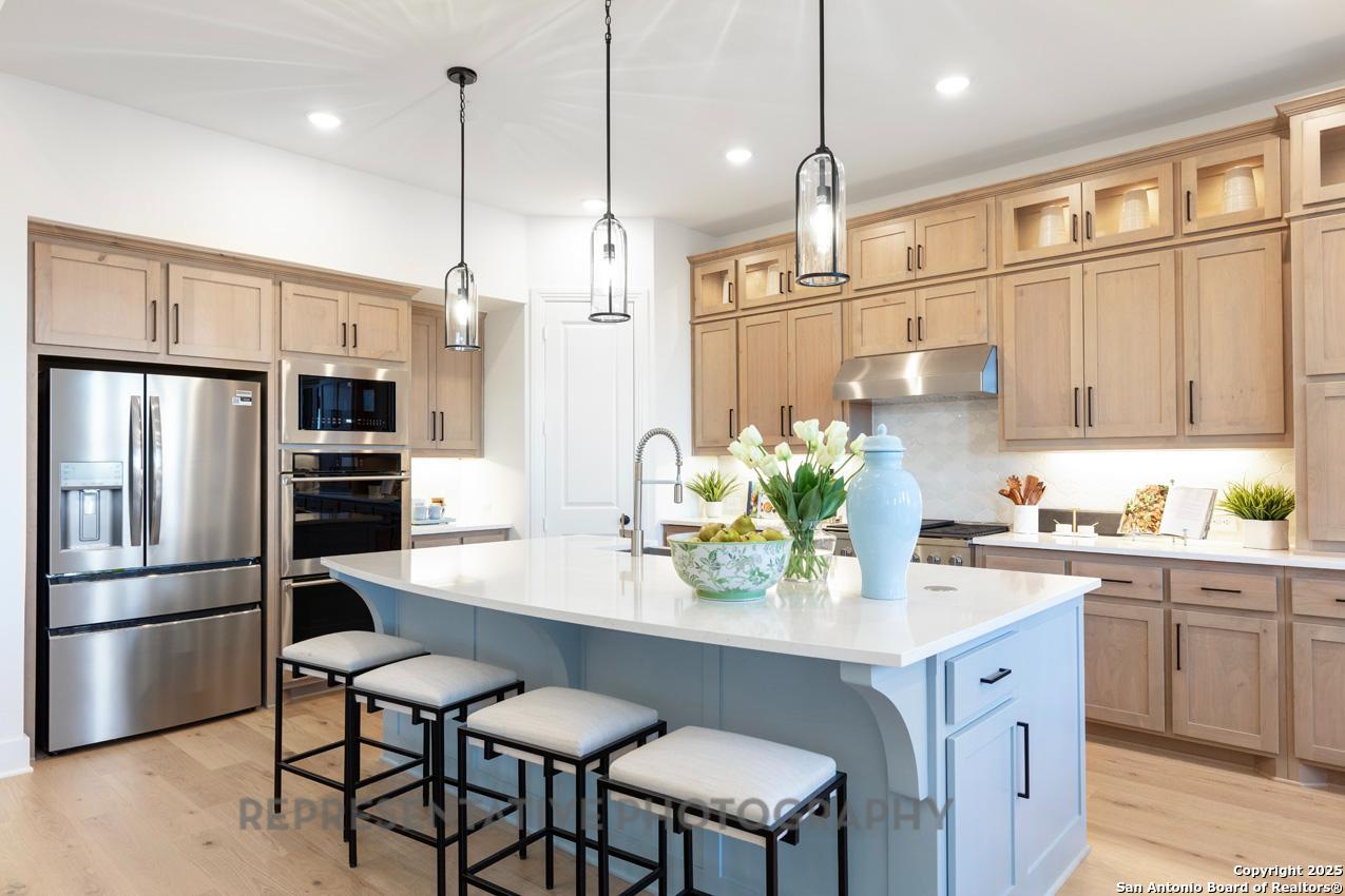 4412 Wendell Way Schertz, TX 78108 - Photo 2 of 28 a kitchen with stainless steel appliances granite countertop a refrigerator a sink dishwasher a stove a kitchen island with chairs and wooden cabinets