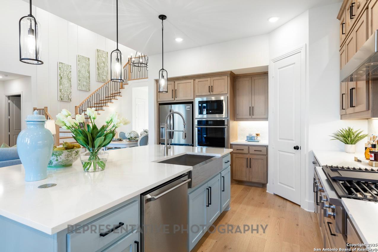 4412 Wendell Way Schertz, TX 78108 - Photo 7 of 28 a kitchen with stainless steel appliances kitchen island granite countertop a sink a stove and a wooden floors