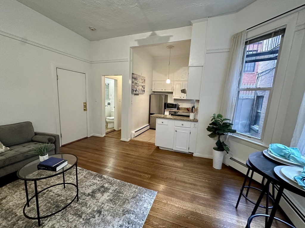 30 Pinckney Street, Unit 2 Boston, MA 02114 - Photo 5 of 18 a living room with furniture dining table wooden floor and a kitchen view