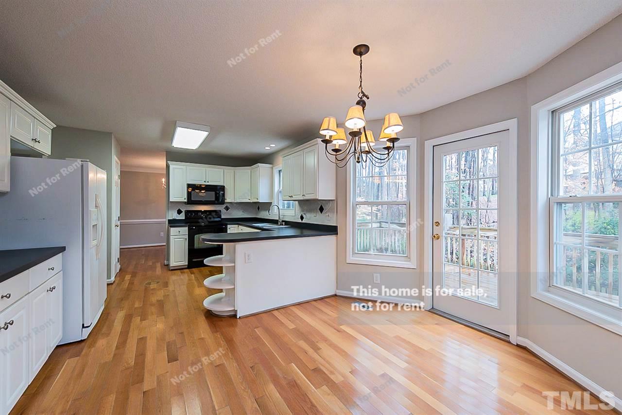 8715 Harps Mill Road Raleigh, NC 27615 - Photo 8 of 22 a kitchen with stainless steel appliances kitchen island granite countertop a refrigerator a stove a sink dishwasher a oven with white cabinets and wooden floor