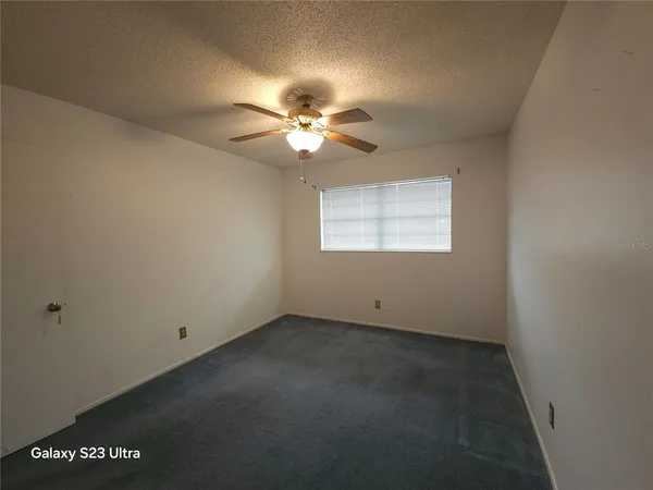 an empty room with a window and a fan
