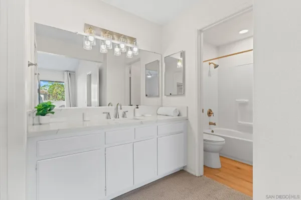 a spacious bathroom with a double vanity sink toilet mirror and a bathtub