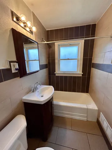 a bathroom with a sink a toilet a mirror and bathtub