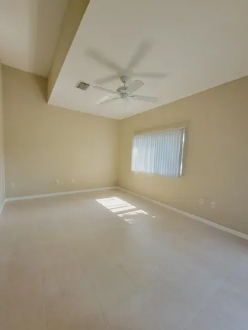 an empty room with windows and fan