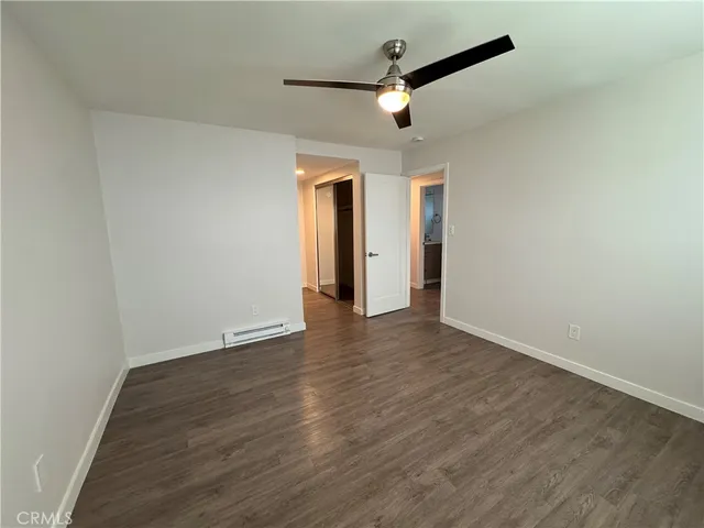 an empty room with wooden floor and chandelier fan