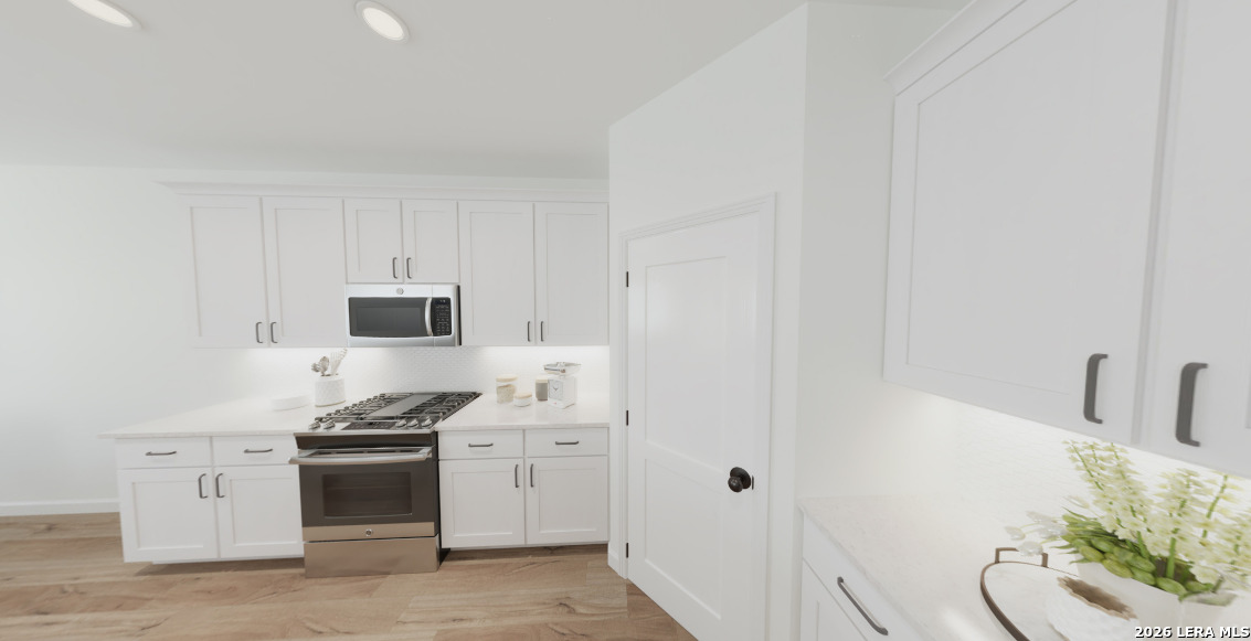410 Nottabi Road Adkins, TX 78101 - Photo 6 of 33 a kitchen with stainless steel appliances a white stove top oven and white wooden cabinets