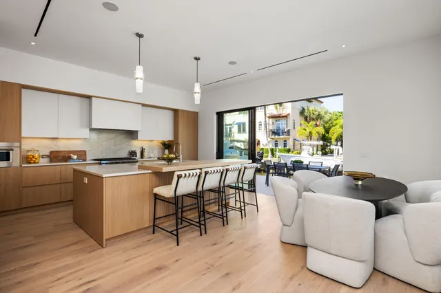 a kitchen with stainless steel appliances granite countertop a dining table chairs refrigerator sink and cabinets