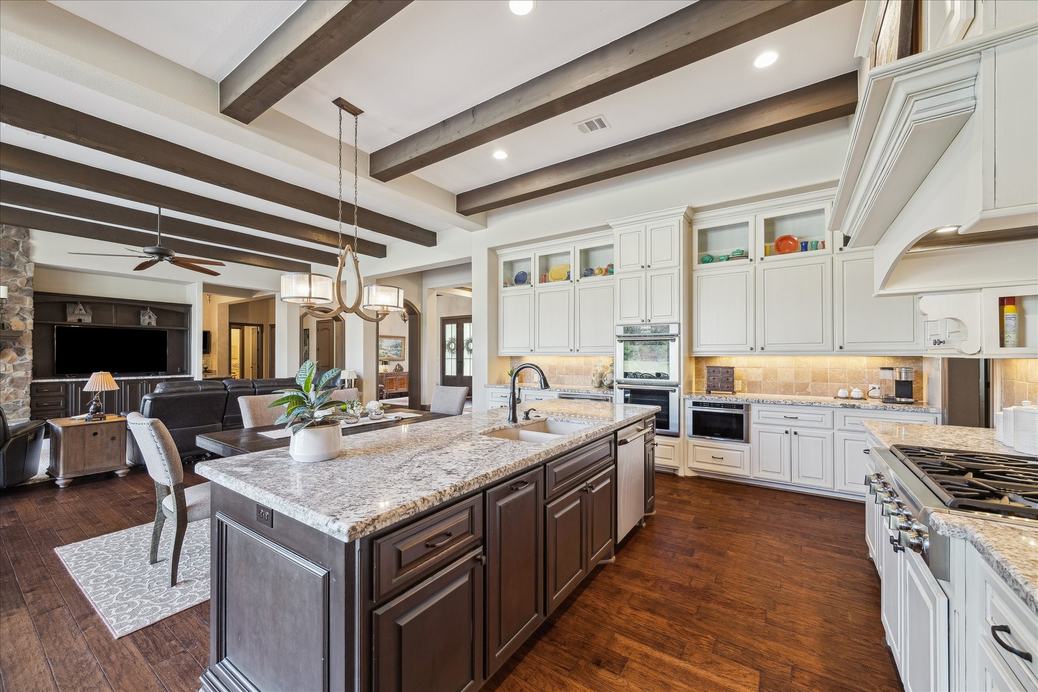 11 Willowcreek Ranch Road Tomball, TX 77377 - Photo 23 of 49 The culinary space features abundant storage including full extension double stacked cabinets to the ceiling. Glass display cabinets allow the chef to show off their favorite pieces. Granite countertops are lit with undercabinet lighting. Wood flooring and accent beams continue to add architectural appeal to this space.